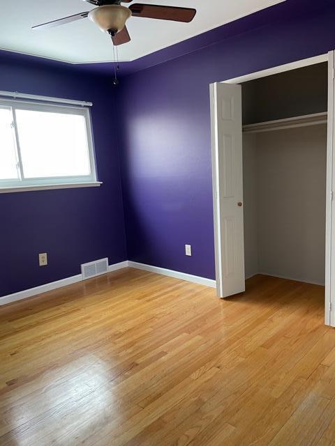 unfurnished bedroom with light wood-style floors, a closet, ceiling fan, and baseboards