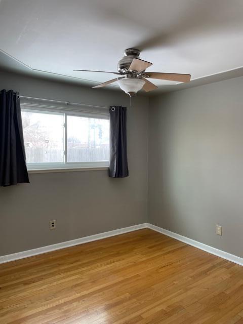 empty room featuring ceiling fan, light wood-style floors, and baseboards