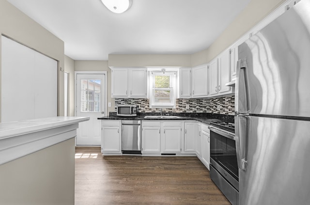 kitchen featuring appliances with stainless steel finishes, dark wood-type flooring, white cabinetry, and decorative backsplash