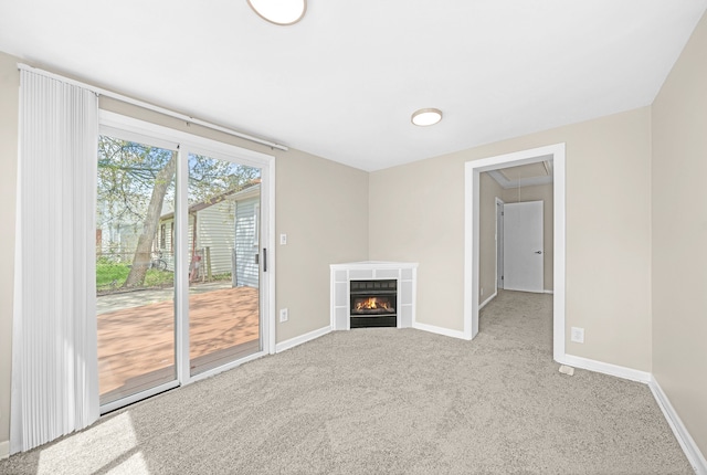 unfurnished living room featuring attic access, carpet floors, baseboards, and a tiled fireplace
