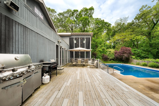 50102 Alpine Blvd, New Buffalo, MI 49117 - view of pool featuring outdoor dining space, a wooden deck, view of wooded area, a sunroom, and grilling area