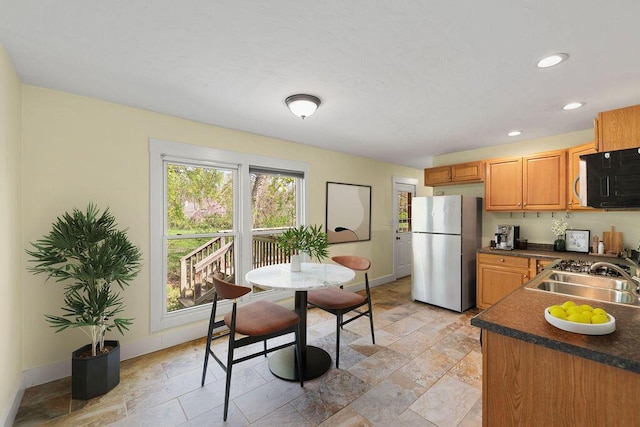 1603 E Detroit St, New Buffalo, MI 49117 - kitchen featuring freestanding refrigerator, a sink, dark countertops, baseboards, and stone tile flooring