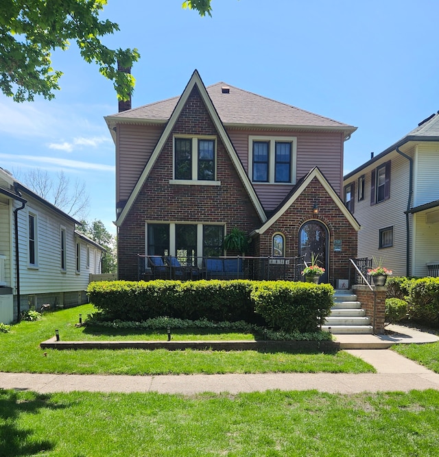 tudor-style house with brick siding and a front lawn