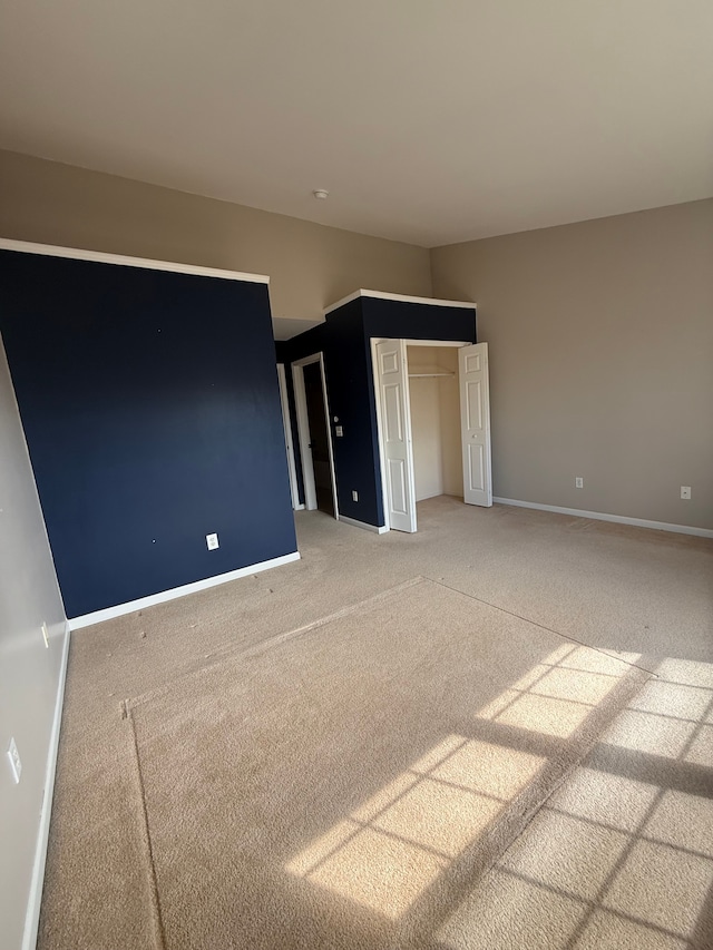 unfurnished bedroom featuring light carpet, baseboards, and a closet