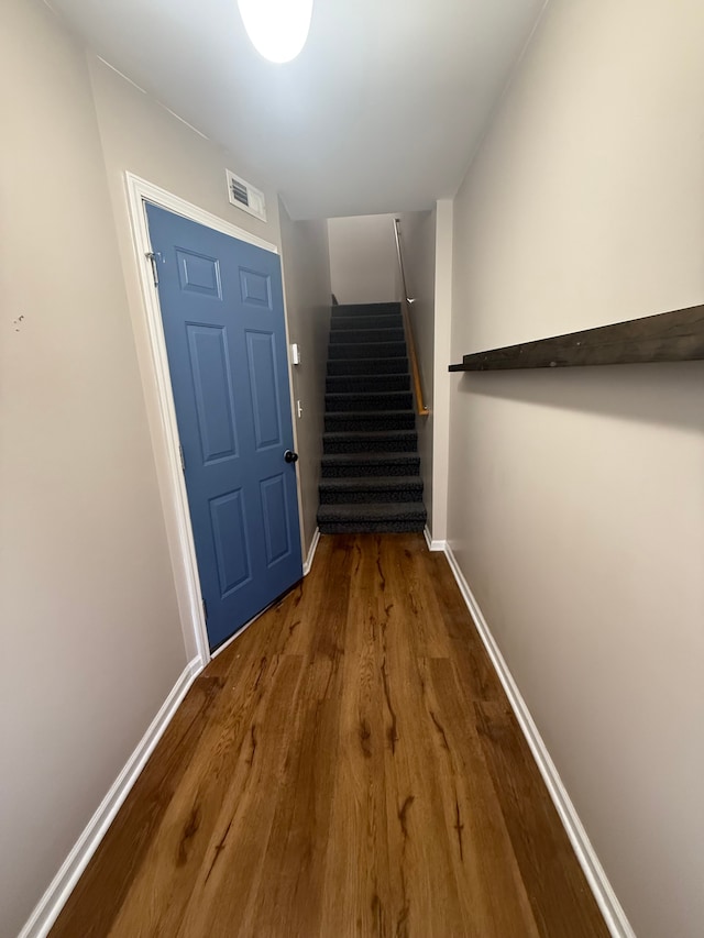 doorway with dark wood-type flooring, stairway, and baseboards
