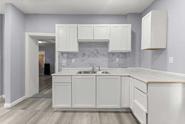 1881 W Grand Blvd, Detroit, MI 48208 - kitchen featuring a sink, light wood-type flooring, decorative backsplash, white cabinets, and light countertops