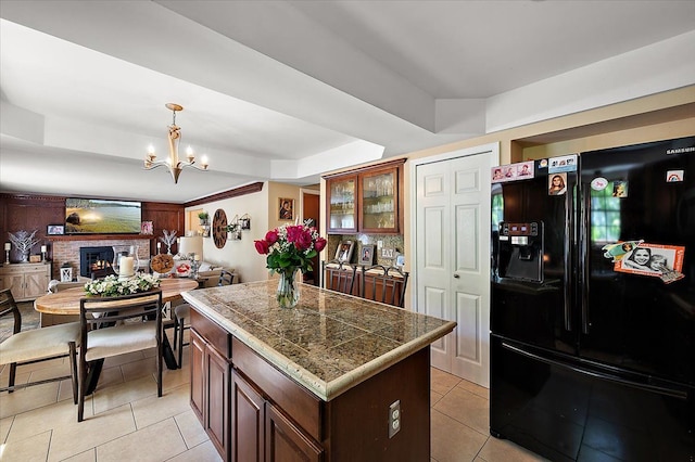 15672 Robert Dr, Macomb, MI 48044 - kitchen featuring black refrigerator with ice dispenser, a tray ceiling, tile counters, light tile patterned floors, and a chandelier