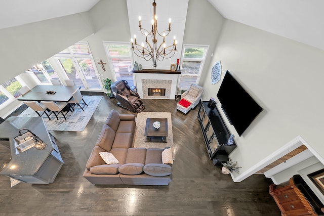 living area with high vaulted ceiling, wood finished floors, a chandelier, a tile fireplace, and baseboards
