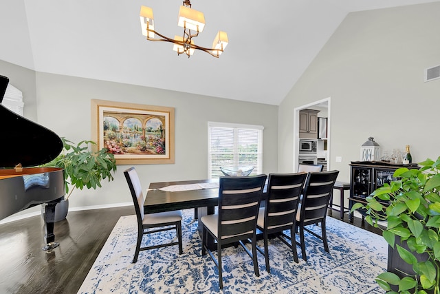dining room with a chandelier, wood finished floors, baseboards, and high vaulted ceiling