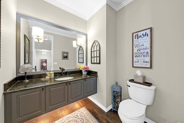 bathroom with crown molding, wood finished floors, toilet, vanity, and baseboards