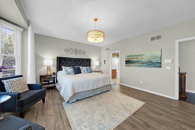 bedroom featuring wood finished floors, baseboards, and ensuite bathroom