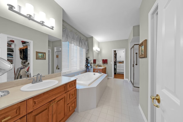 full bath with tile patterned floors, a shower stall, a garden tub, vanity, and a walk in closet