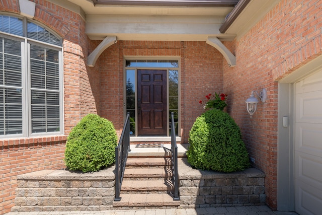 doorway to property with brick siding and a garage