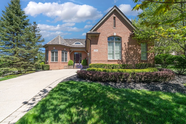 view of front of house featuring brick siding, a front lawn, and driveway