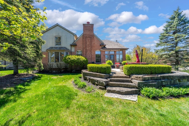 rear view of house with a yard, a chimney, and brick siding