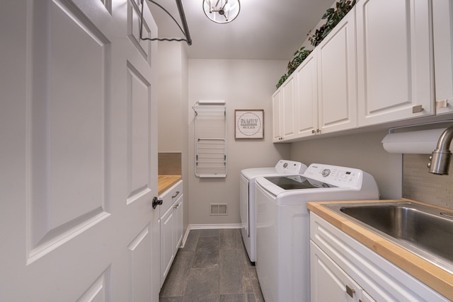 clothes washing area featuring separate washer and dryer, cabinet space, and baseboards