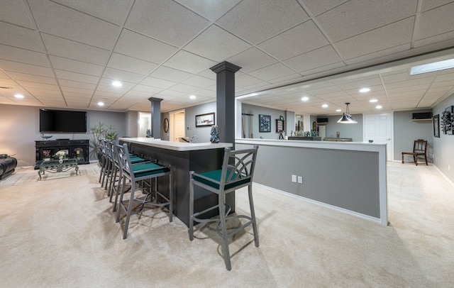 kitchen with open floor plan, light colored carpet, ornate columns, a breakfast bar, and a peninsula