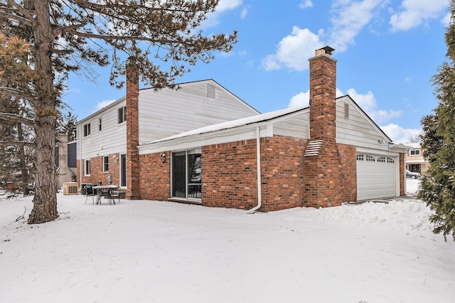 4819 Thorntree Dr, West Bloomfield, MI 48322 - snow covered back of property with a chimney, brick siding, and an attached garage