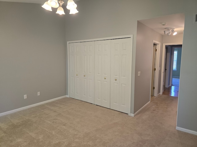 unfurnished bedroom with light carpet, a chandelier, and baseboards