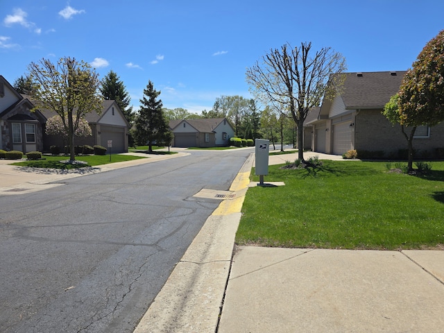 view of asphalt road with a residential view and curbs