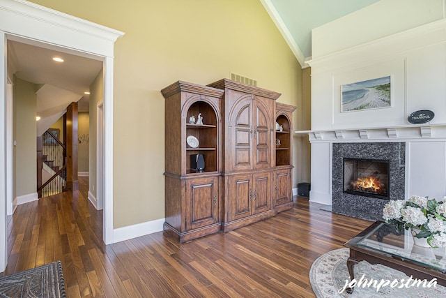 living room with high vaulted ceiling, a fireplace, dark wood-type flooring, baseboards, and crown molding