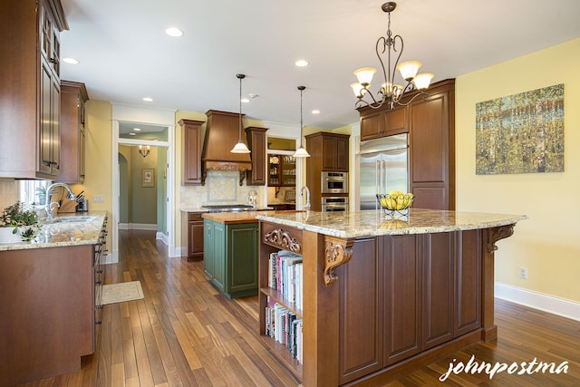 kitchen with appliances with stainless steel finishes, a center island with sink, custom range hood, a sink, and tasteful backsplash