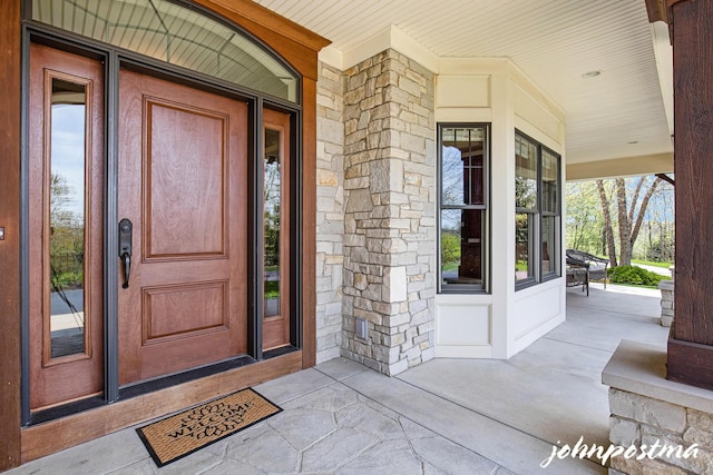 entrance to property featuring covered porch and stone siding