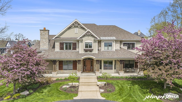 view of front facade with a chimney, a front lawn, and stone siding