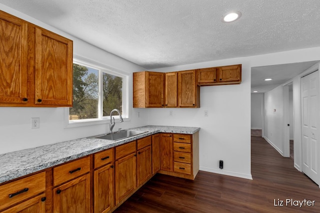 311 W Fenwick Rd, Fenwick, MI 48834 - kitchen featuring a sink, brown cabinets, dark wood-type flooring, a textured ceiling, and baseboards