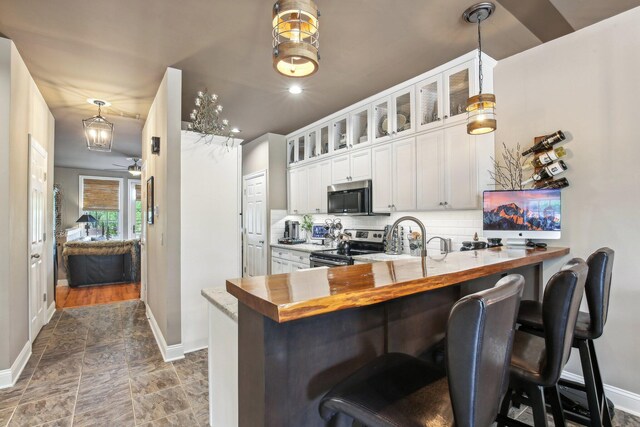 141 Paton Way, Romeo, MI 48065 - kitchen with appliances with stainless steel finishes, baseboards, backsplash, a peninsula, and a breakfast bar