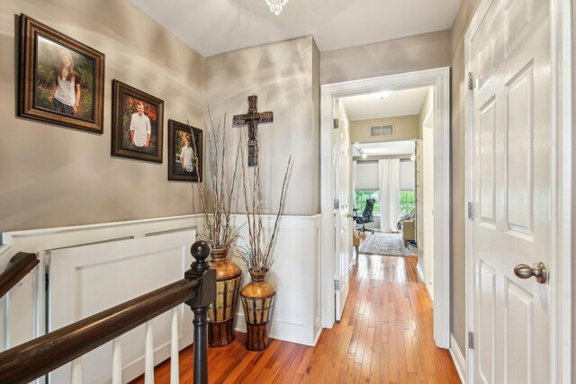 141 Paton Way, Romeo, MI 48065 - corridor with light wood finished floors, an upstairs landing, a wainscoted wall, and a decorative wall