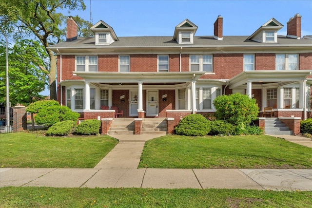 view of front facade with covered porch, brick siding, and a front yard