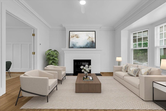 living area featuring ornamental molding, wood finished floors, and a brick fireplace