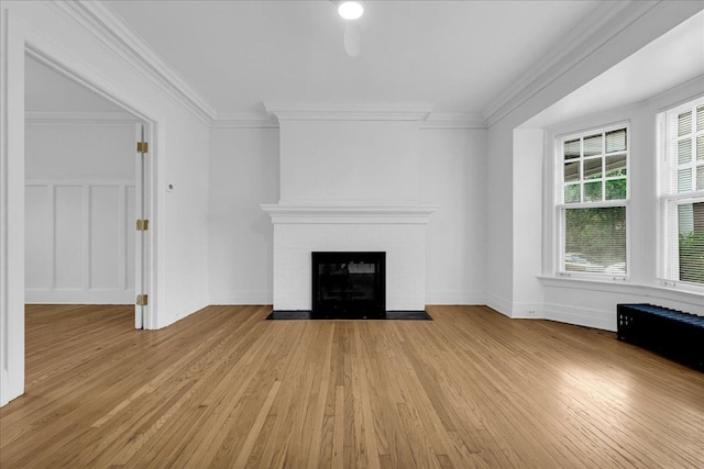 unfurnished living room featuring light wood-style floors, a brick fireplace, ornamental molding, and baseboards