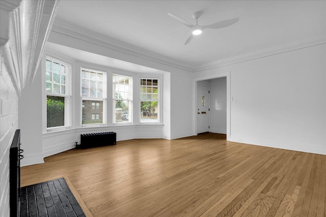 unfurnished living room with a ceiling fan, wood finished floors, crown molding, and healthy amount of natural light