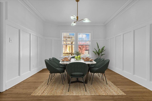 dining room featuring a decorative wall, a chandelier, ornamental molding, wood finished floors, and wainscoting