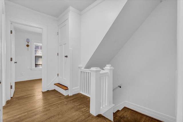 corridor featuring an upstairs landing, wood finished floors, baseboards, and ornamental molding