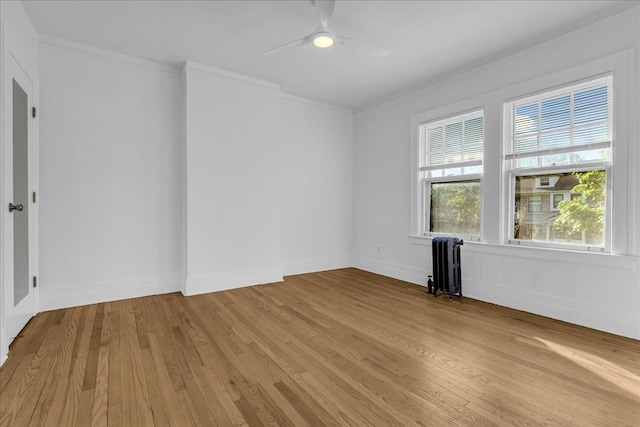 unfurnished room with radiator, a ceiling fan, light wood-type flooring, crown molding, and baseboards