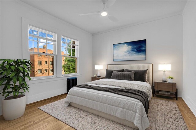 bedroom with crown molding, baseboards, wood finished floors, ceiling fan, and radiator