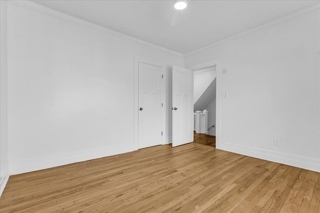 unfurnished room with light wood-style floors, ornamental molding, and baseboards