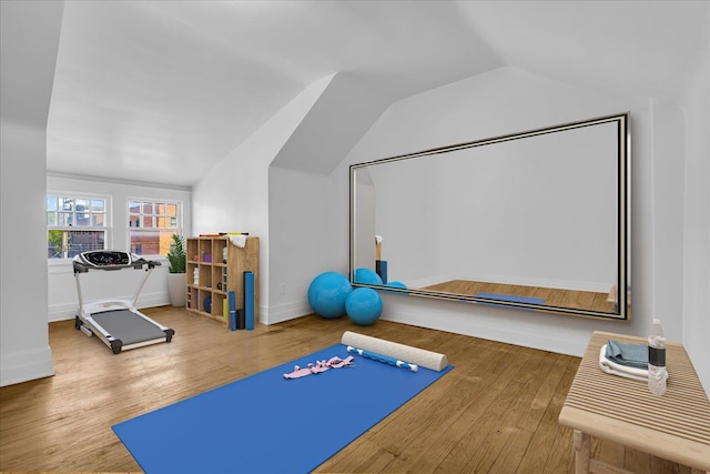 workout area featuring vaulted ceiling, wood finished floors, and baseboards