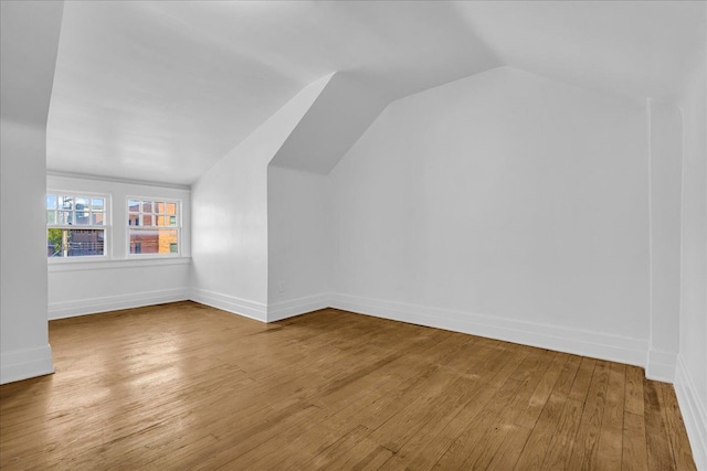 bonus room with vaulted ceiling, wood finished floors, and baseboards