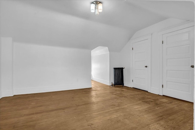 bonus room with vaulted ceiling, radiator, wood finished floors, and baseboards