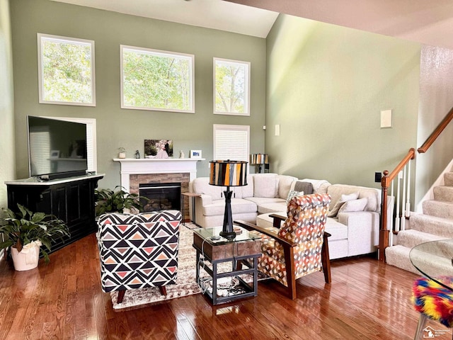 living room with a glass covered fireplace, stairs, dark wood-type flooring, and plenty of natural light