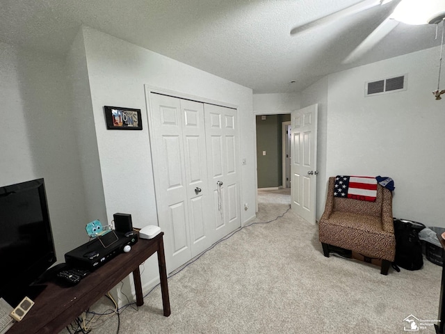 living area with carpet flooring, a ceiling fan, and a textured ceiling