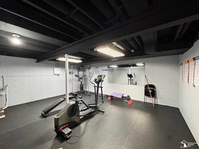 workout room featuring brick wall