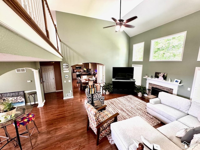 living area with arched walkways, high vaulted ceiling, a ceiling fan, wood finished floors, and decorative columns