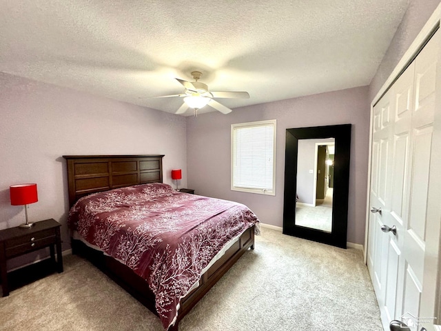 bedroom featuring light colored carpet, a closet, a textured ceiling, a ceiling fan, and baseboards