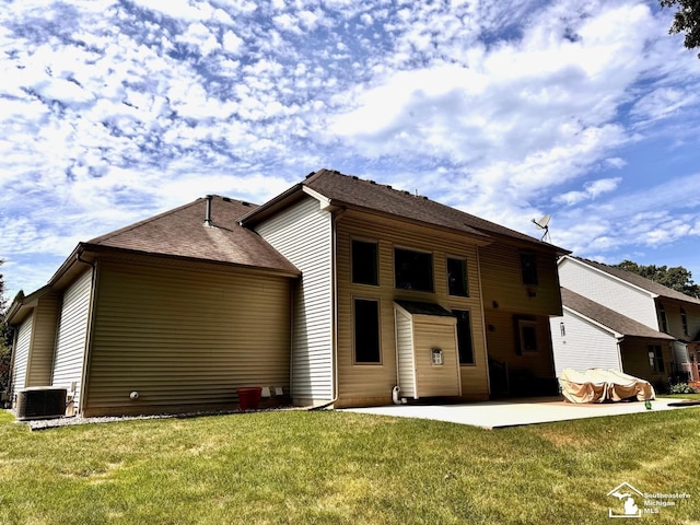 back of property with a patio, a lawn, and central AC