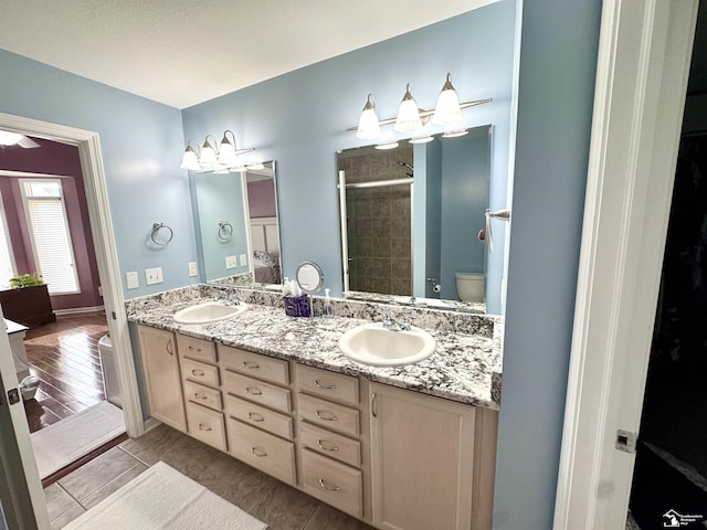 full bathroom featuring a stall shower, double vanity, and toilet